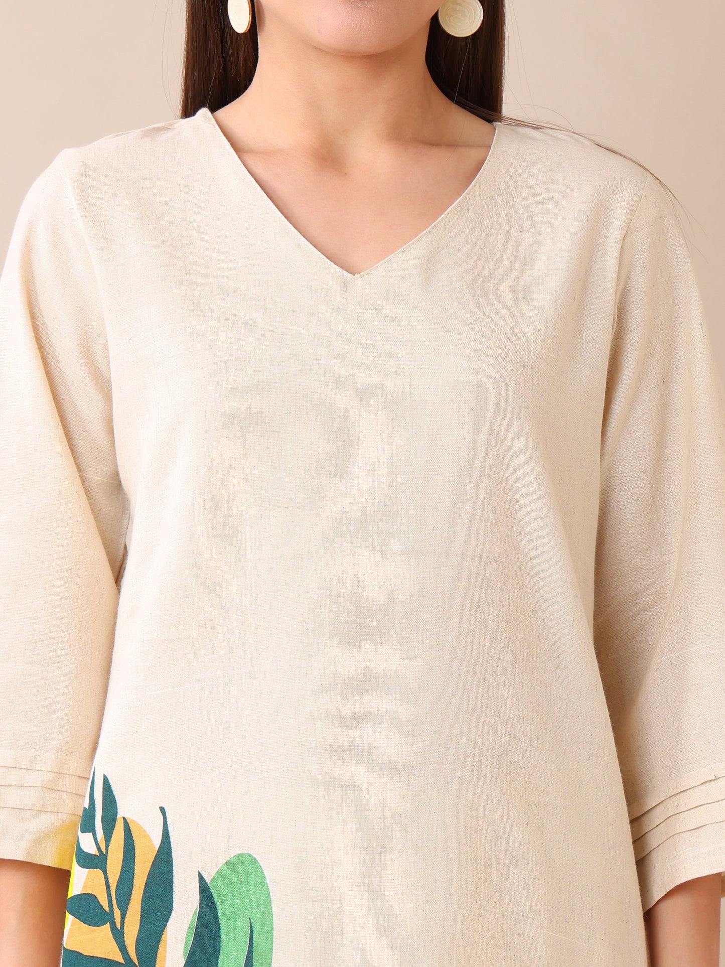 Beige top with leaf pattern on sleeve against a neutral background