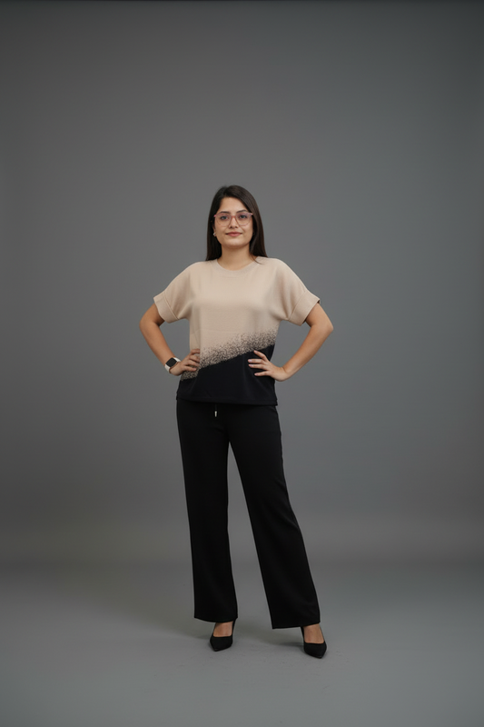 Woman wearing a beige top and black pants on a gray background