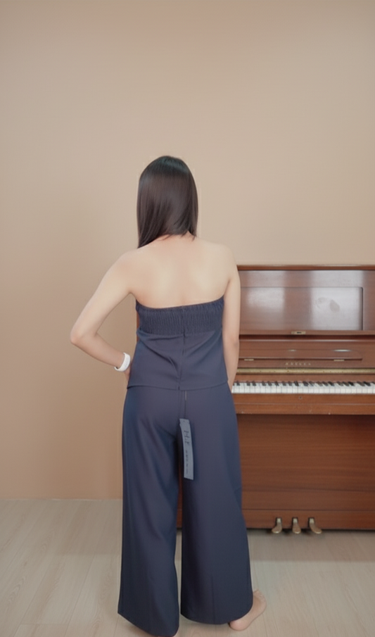 Model wearing navy blue strapless co-ord set with bow detail top and wide-leg trousers – elegant party wear look.