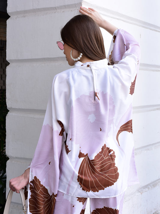 Woman wearing a floral kimono-style garment against a white wall.