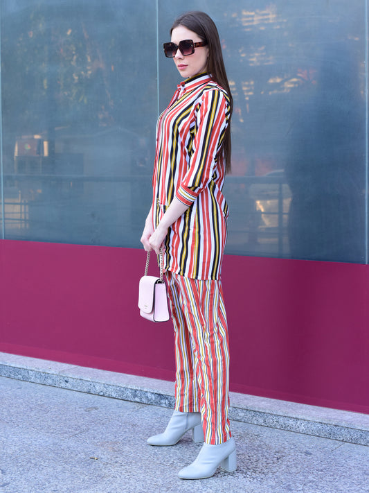 Woman in a colorful striped outfit standing against a reflective glass wall, stylish and versatile co-ord set for women.