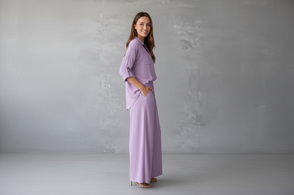 Woman wearing a lavender outfit standing against a plain gray background