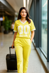 Woman in yellow 'New York' outfit holding a suitcase in an indoor setting
