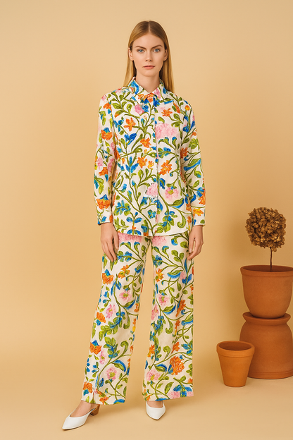 Woman wearing a colorful floral outfit against a beige background with potted plants.
