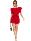 Close-up of red knitted short jumpsuit showing puff sleeve design, waist tie detail and smooth stretch fabric