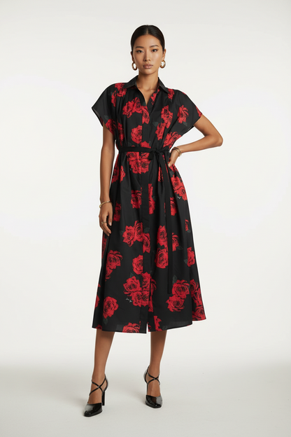 Woman wearing a black dress with red floral pattern on a white background
