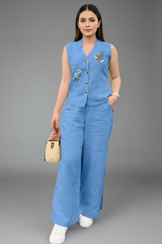 Woman wearing a blue sleeveless top and wide-leg pants with a gray background