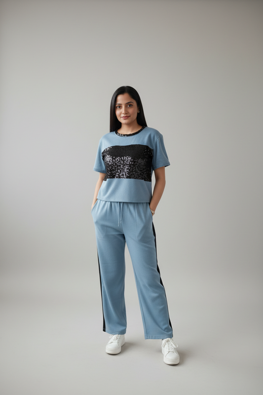 Woman wearing a blue outfit with a black sequin top against a gray background