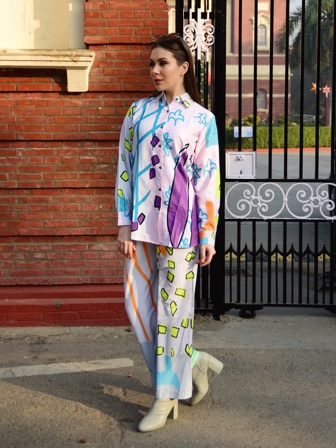 Woman wearing a colorful outfit with a brick wall and gate in the background, stylish women’s co-ord.