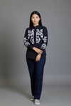 Woman wearing a navy blue outfit with white patterns on a gray background