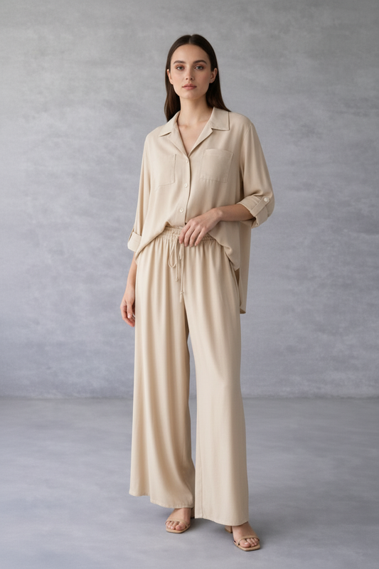 Woman wearing a beige outfit against a gray background