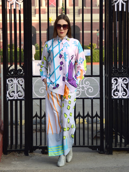 Woman wearing a colorful outfit with abstract patterns in front of a black, gate, stylish women’s co-ord.