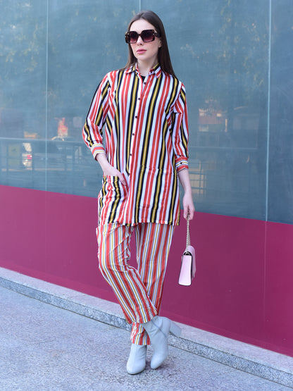 Woman in a colorful striped outfit standing against a glass wall with a pink base, stylish and versatile co-ord set for women 