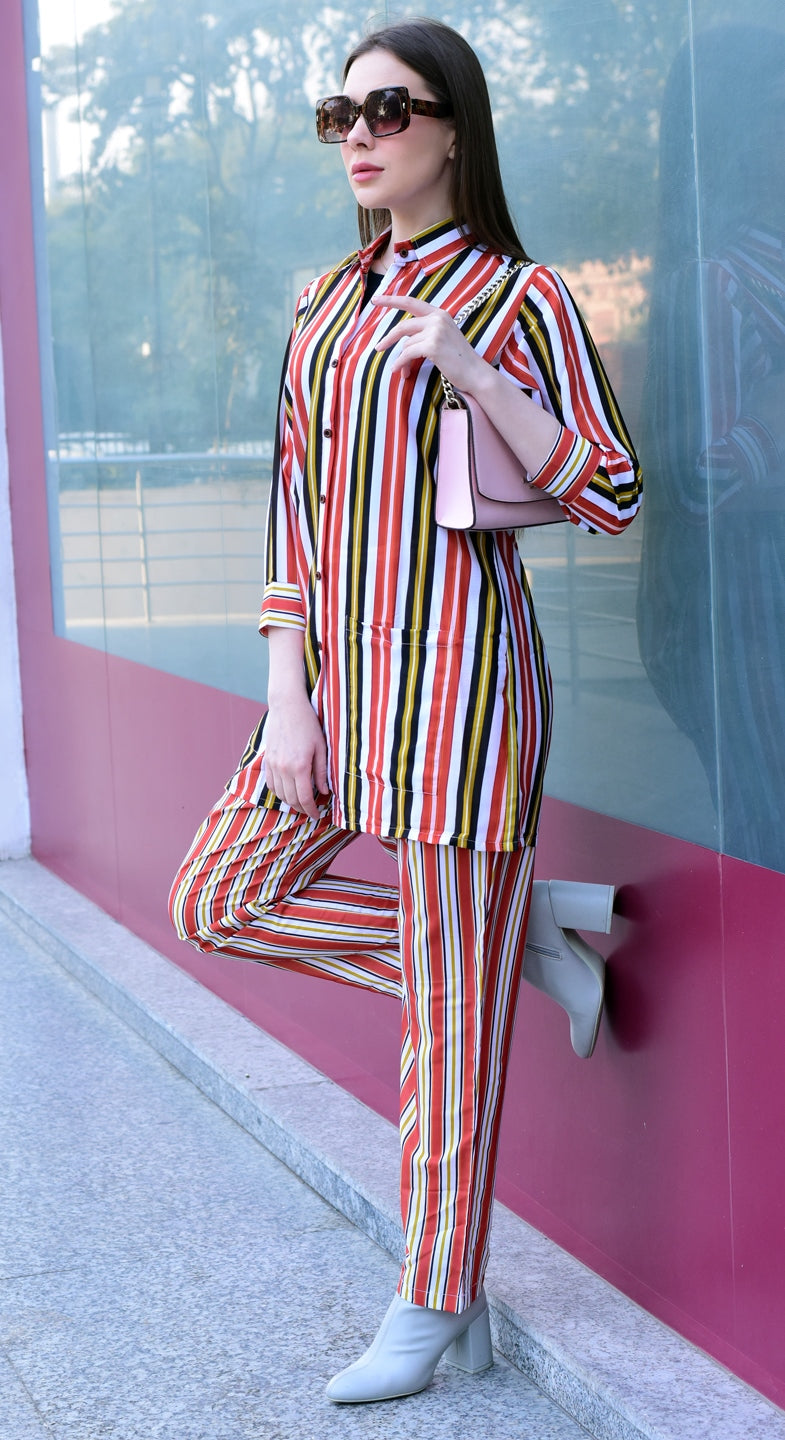 Woman in a colorful striped outfit standing against a pink wall,stylish and versatile co-ord set for women.
